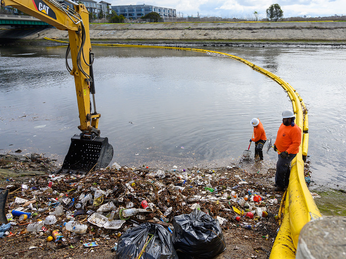 Photo of LA County Public Works crew clearing debris captured by booms in the Ballona Creek.